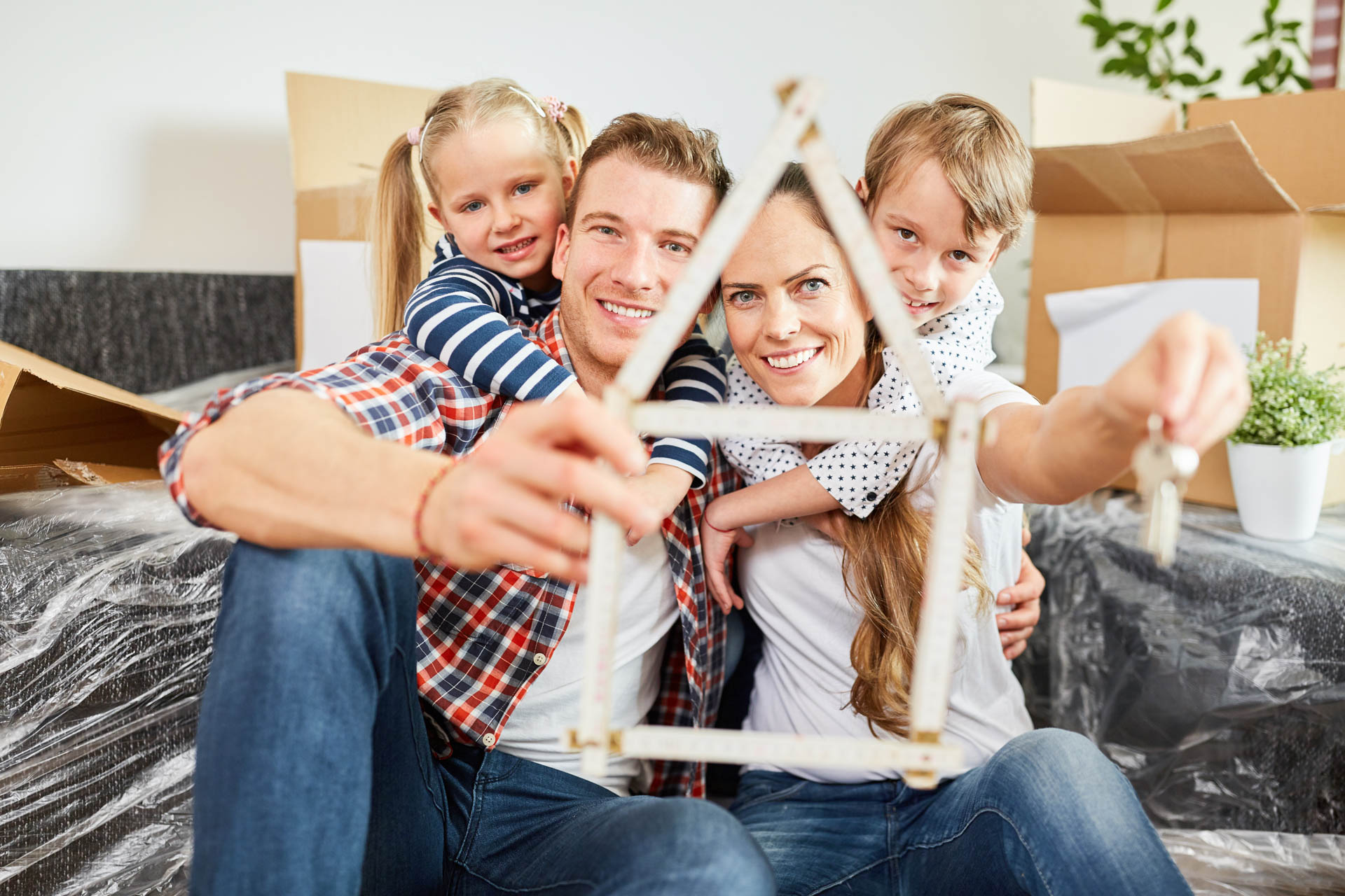 Familie und Kinder mit Zollstock in Form von Haus als Symbol für ihr Traumhaus